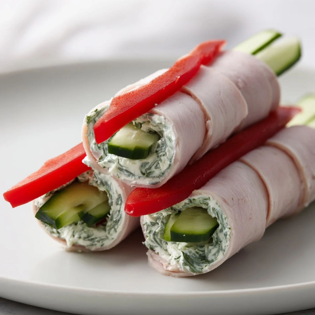 Freshly rolled turkey roll-ups, vibrant with red bell peppers and crisp cucumber inside, ready to serve.