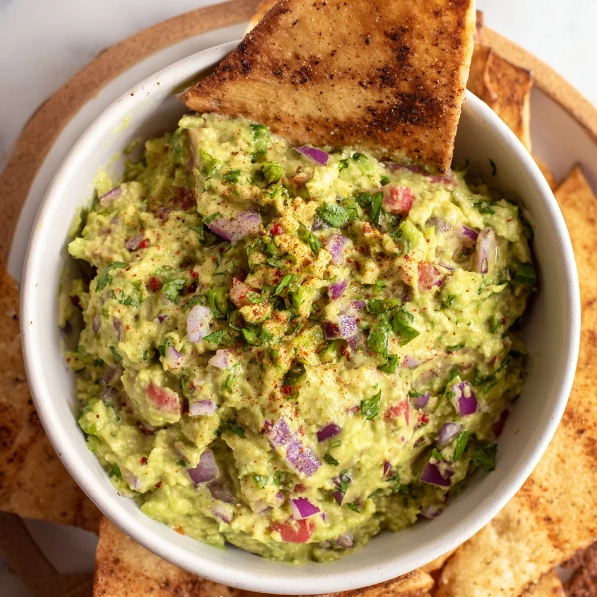 Golden brown pita chips alongside a vibrant green guacamole bowl, ready for dipping and enjoying.