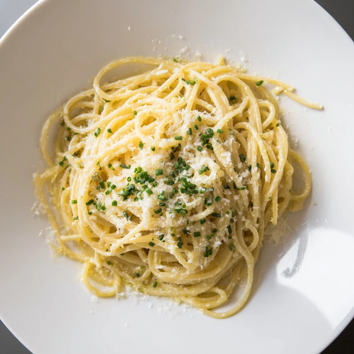 Steaming bowl of Miso Butter Pasta: creamy noodles coated with savory miso sauce and fresh chives.
