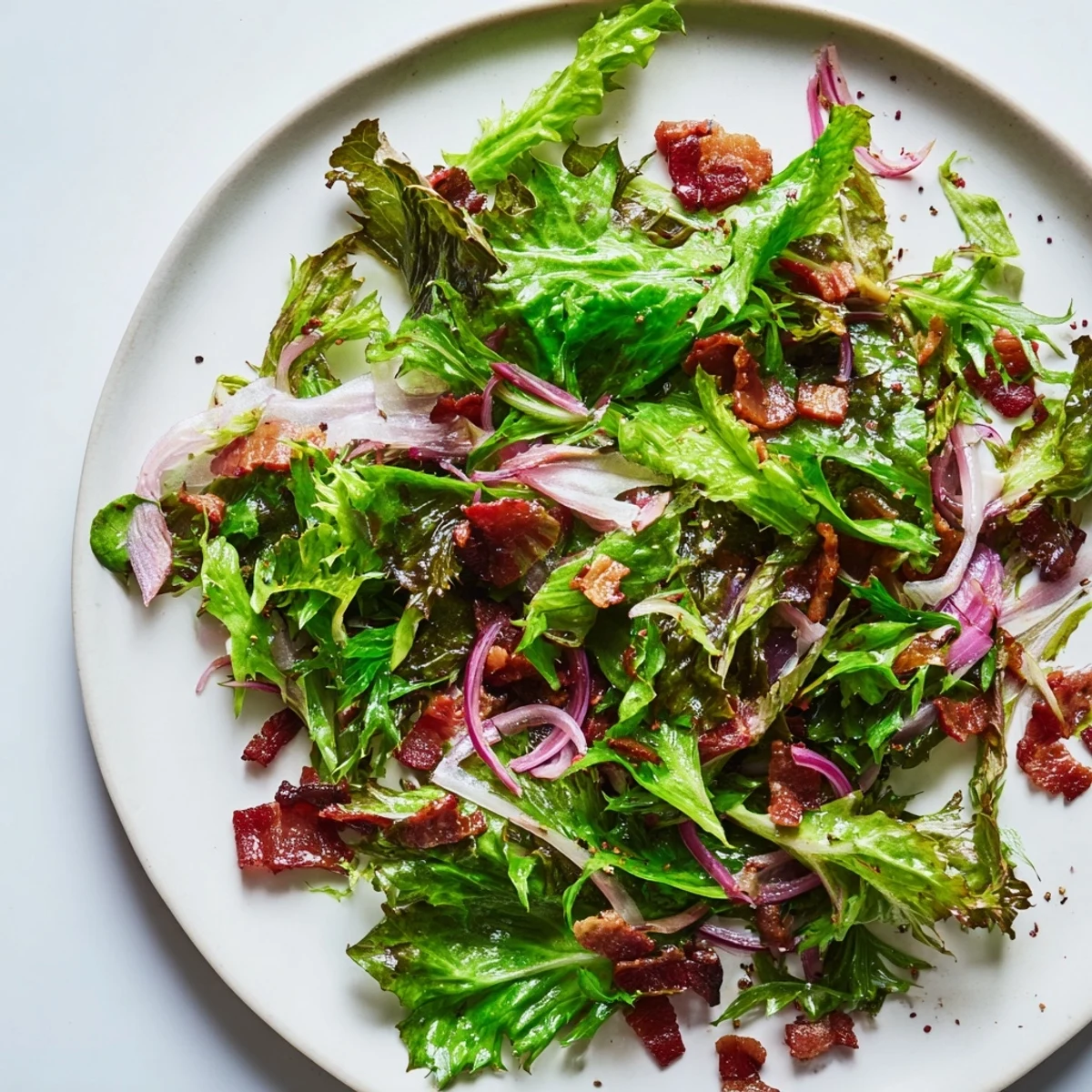 This Bitter Greens Salad boasts a warm bacon dressing, coating tender greens with a flavorful vinaigrette.