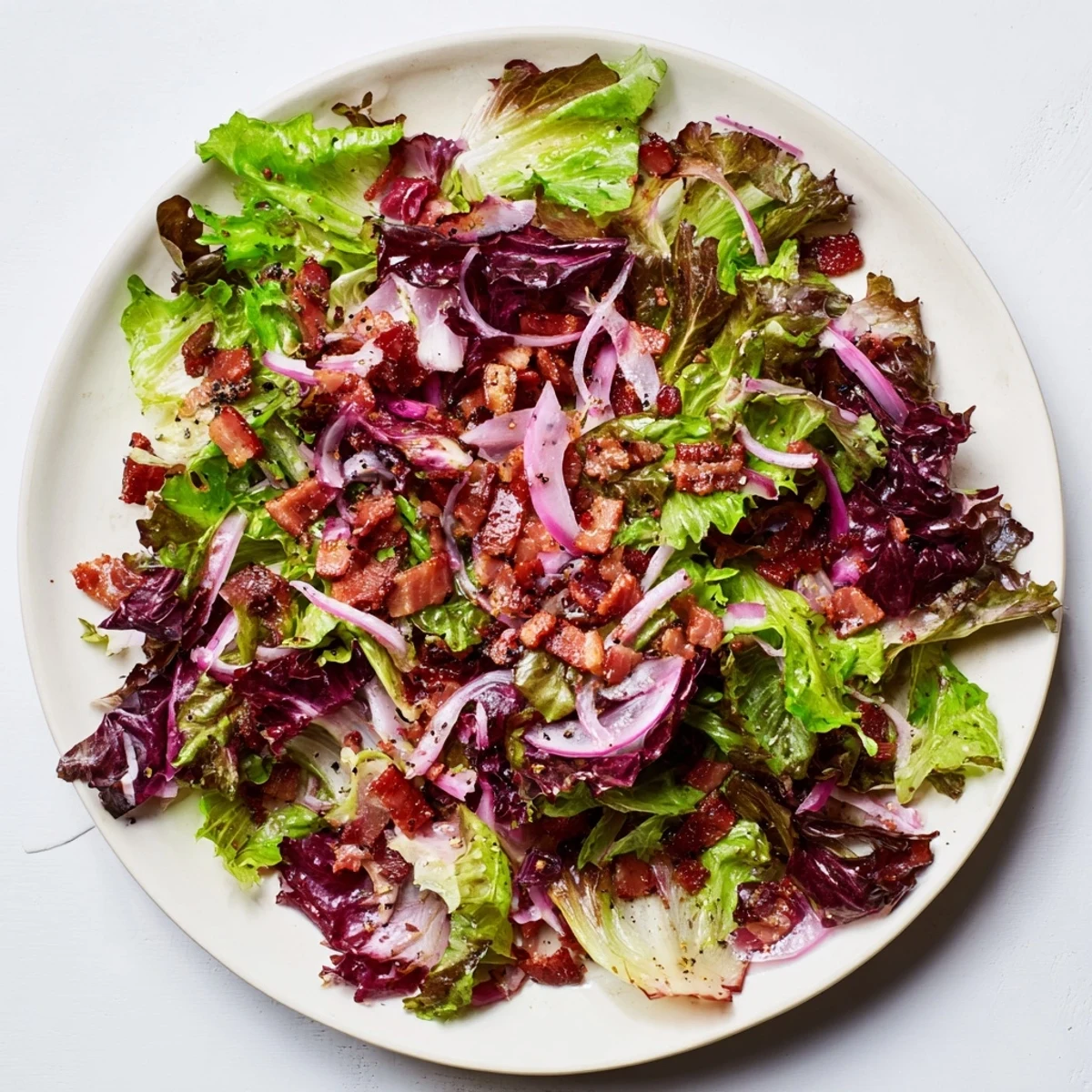 Enjoy the delicious Bitter Greens Salad with Warm Bacon Dressing: a hearty, flavorful salad with crispy bacon.