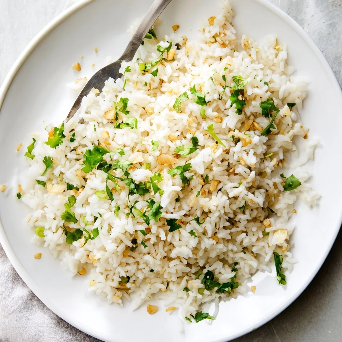 Fluffy jasmine rice garlic side dish, with golden minced garlic infused in oil and garnished with fresh cilantro, served warm.