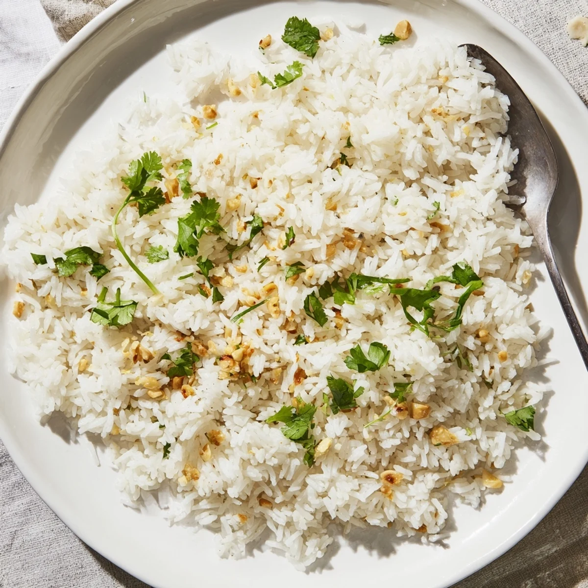 A steaming bowl of jasmine rice garlic, the tender grains glistening with savory garlic oil and topped with vibrant green cilantro.