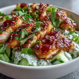 A vibrant bowl of TikTok Chili-Crisp Cucumber Chicken Bowls with jasmine rice, cilantro, and lime wedges.