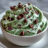 Creamy St. Patrick's Day mint chocolate chip dip with green swirls and mini chocolate chips, served with graham crackers for dipping.