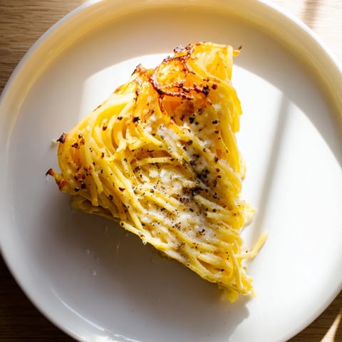 Golden, crispy Cacio e Pepe Pasta Pie, bubbling with creamy cheese, ready to slice and serve.