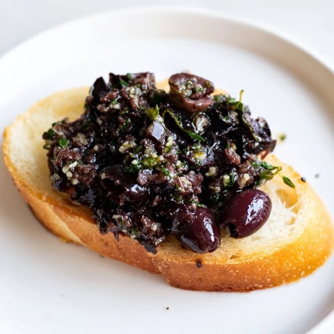 Savory black olive tapenade served over golden, crisp crostini, a perfect appetizer.