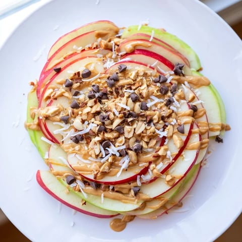 Freshly sliced apples drizzled with peanut butter and honey, forming a yummy Peanut Butter Apple Nachos snack.