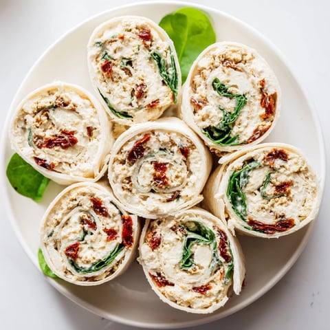 Sun-dried tomato turkey roll-ups are filled with creamy cheese, fresh basil, and spinach; delicious appetizer.