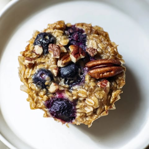 A golden-brown baked oatmeal cup, brimming with berries, ready for a delicious breakfast.