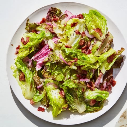 Vibrant Bitter Greens Salad with Warm Bacon Dressing, a delightful, savory starter, garnished with eggs.