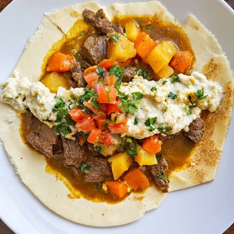 Steaming bowl of Yemeni Saltah stew with fluffy fenugreek topping, ready to eat alongside warm bread.