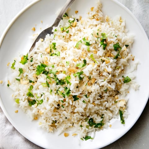 Fluffy jasmine rice garlic side dish, with golden minced garlic infused in oil and garnished with fresh cilantro, served warm.