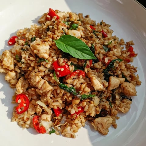Steaming Thai Basil Chicken Fried rice served with lime wedges and cucumber slices for a fresh, spicy meal.  
