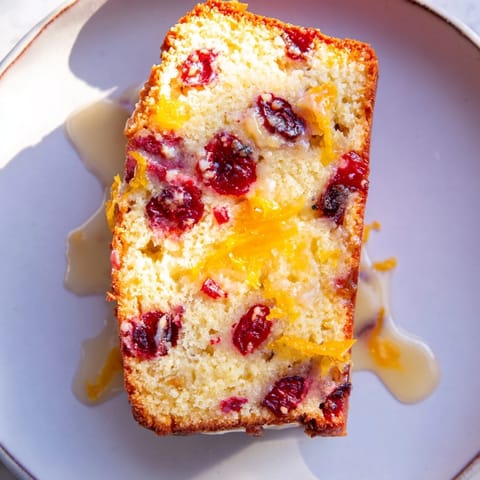 Fresh cranberries stud this Quick Cranberry Orange Loaf Cake, a festive American dessert, ready to enjoy.
