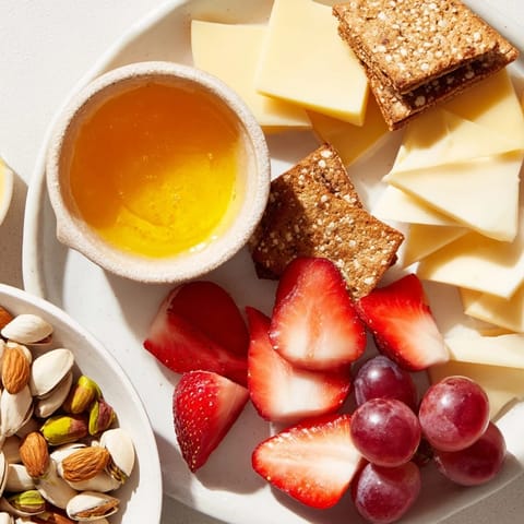 A brightly arranged Bears Honey Pot Board with fresh fruit, cheese, crackers, and dipping honey.
