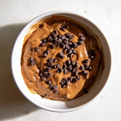 A close-up of a luscious brownie batter dip, ready to be enjoyed with fresh fruit.