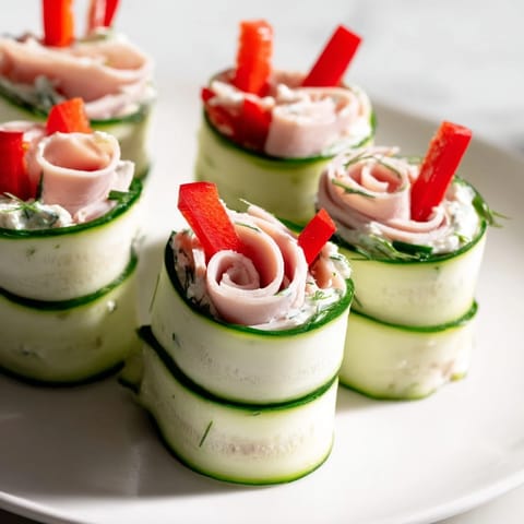 Close-up of refreshing cucumber roll-ups; creamy filling peeks through crisp cucumber slices.