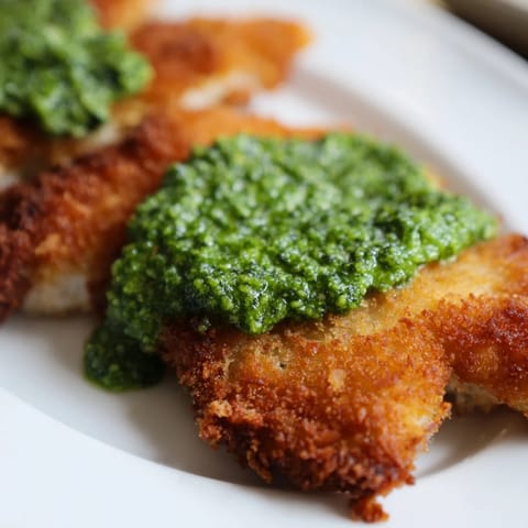 Crispy pesto chicken cutlets fried to perfection with a vibrant green dollop on top.  