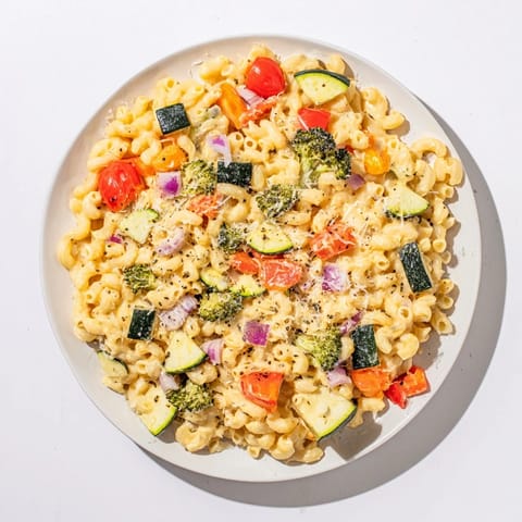 A close-up of Roasted Veggie Mac & Cheese featuring caramelized peppers and zucchini tossed with al dente elbow macaroni.