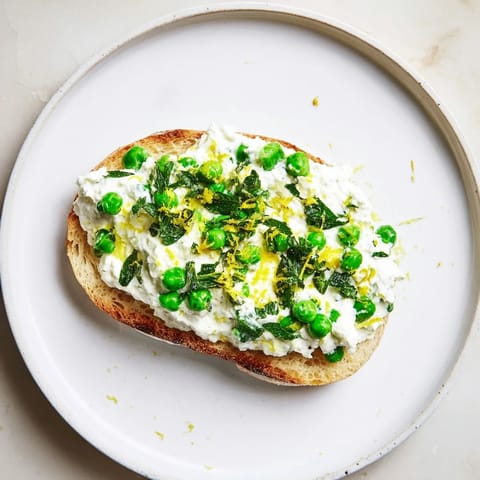 The vibrant Pea & Mint Ricotta Toast features creamy whipped ricotta and sweet peas piled onto golden, crunchy sourdough.  