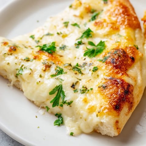 A close-up of Creamy Garlic White Pizza, its velvety garlic cream sauce glistening under melted mozzarella.