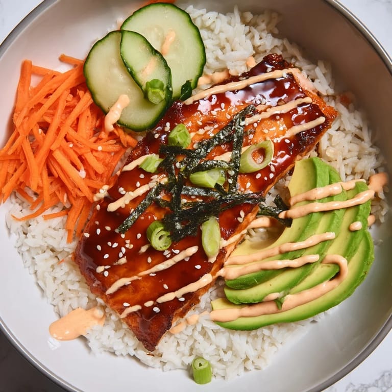 Fluffy white rice topped with flaky teriyaki salmon, avocado, and sriracha mayo in this delicious bowl.