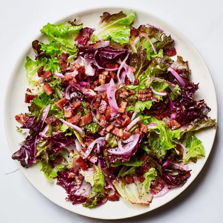 Enjoy the delicious Bitter Greens Salad with Warm Bacon Dressing: a hearty, flavorful salad with crispy bacon.