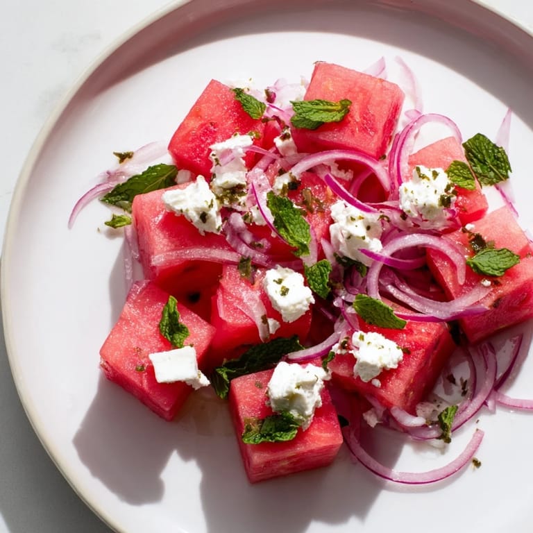 Close-up shot shows a refreshing Watermelon Feta Salad with mint, red onions, and creamy feta cheese.