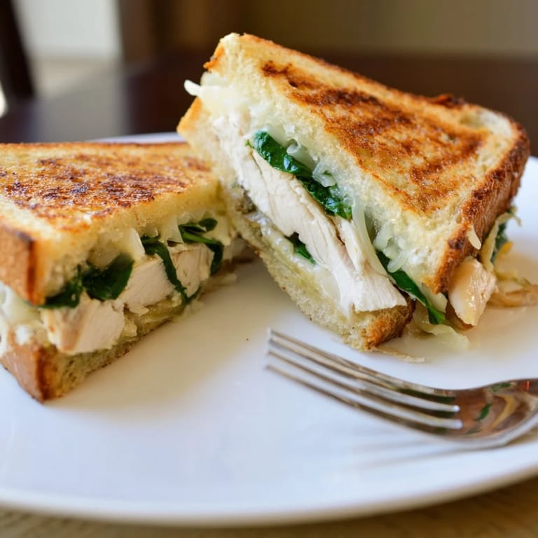 Close-up of a Grilled Chicken Spinach Panini pressed to perfection, with garlic butter dripping from the crispy, golden edges.
